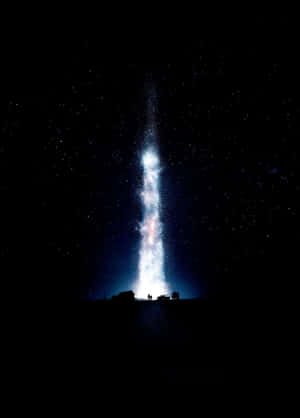 兩個人仰望在星空夜空映襯下發光的宇宙柱。