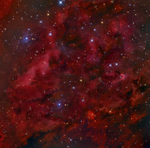 一個紅色和紫色的星雲，充滿了深空中的明亮星星。