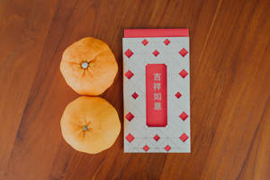 兩個橙和一個帶有中文字的紅色信封在木頭上。