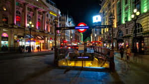 夜晚的倫敦街道，有照明的地鐵入口和歷史建築。