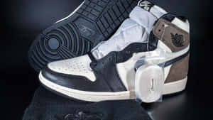 黑白 Air Jordan 1 運動鞋，帶有棕色點綴，未包裝並展示在深色表面上。