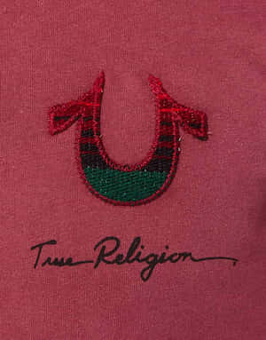 栗色布料上帶綠色閃粉的刺繡馬蹄鐵標誌，下方有「True Religion」字樣。