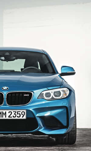 在攝影棚環境中，藍色BMW M2跑車配備銳利頭燈和黑色格柵。