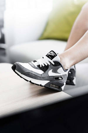 一個人腳部穿著灰色同白色嘅Nike Air Max波鞋喺木質表面上。 — 型格 Nike 壁紙