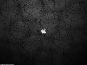 銀色Apple標誌在破裂的黑色混凝土背景上。