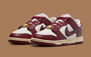 酒紅色和白色的 Nike Dunk Low 運動鞋，棕色背景上帶有金幣細節。