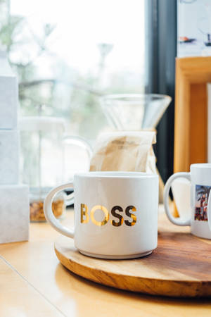 白色馬克杯帶金色boss字樣在木托盤上近窗 — 玫瑰金風格 壁紙