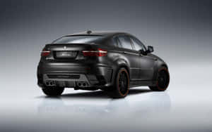 啞光黑色BMW X6M，橙色輪圈和四出排氣管，在攝影棚中反射。 — Steam Deck OLED 壁紙