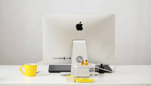 乾淨的白色桌面，配有 Apple iMac、黃色馬克杯和 LEGO 人仔。