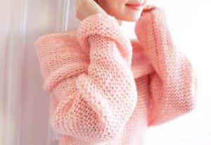 室內穿著柔軟粉紅色粗針織毛衣的人。 — 熱粉紅美學 壁紙