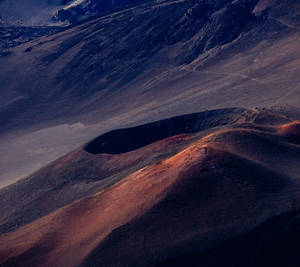 黃昏時分，火山口邊緣沐浴在橙色光芒中，映襯著陰影籠罩的山脈。