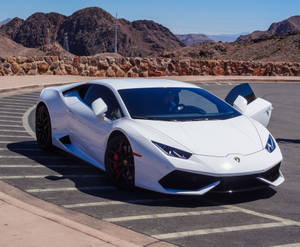 白色林寶堅尼 Huracán 停泊在沙漠停車場，背後有山脈。