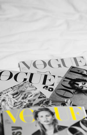 Vogue雜誌散落在白色床單上，其中一本黃色封面。