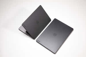 白色背景上的兩部黑色MacBook手提電腦