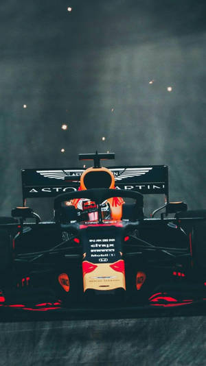 Aston Martin F1賽車，帶有紅色點綴和贊助商標誌，在煙霧和火花下於夜晚。