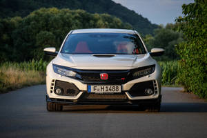 日落時分，白色本田Civic Type R行駛在風景如畫的鄉村道路上。