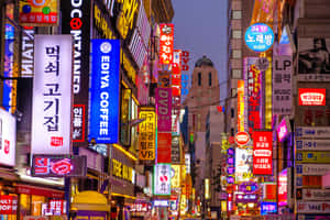 黃昏時霓虹燈照亮韓國城市街道，閃爍的招牌和建築物。 — 韓國 壁紙