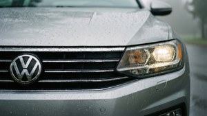 銀色福士汽車前部，帶有雨滴和發光的車頭燈，在霧濛濛的傍晚。