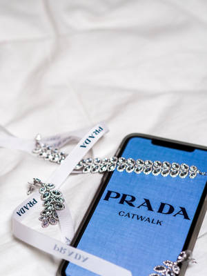 白色布料上的水晶珠寶旁邊的Prada Catwalk手機屏幕。