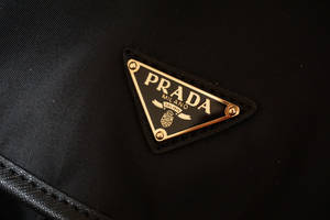 黑色布料上帶金色邊框和縫線的Prada標誌貼章。