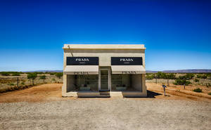 在清澈藍天下，沙漠景觀中的 Prada Marfa 藝術裝置。