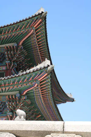 藍天下色彩繽紛的傳統韓國寺廟屋頂，帶有石獅雕像。