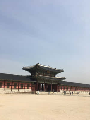 藍天下傳統韓國宮殿，紅牆和彎曲屋頂。