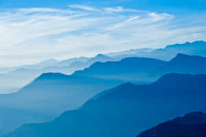 寧靜的山景，帶有藍色霧氣和輕柔的雲朵。 — 藍天 壁紙