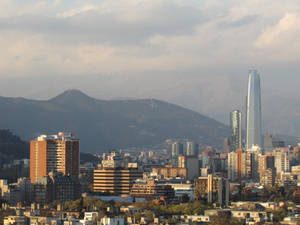 陰天下，高樓大廈和山脈在後的城市天際線。 — 建築 壁紙