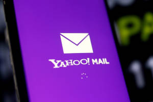 Yahoo Mail 應用程式在紫色背景的智能手機屏幕上載入中。