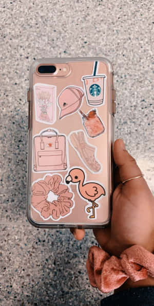 手裡拿著手機，裝飾有粉紅色火烈鳥、咖啡和配飾貼紙。