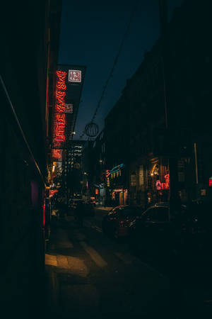 夜晚被紅色霓虹燈招牌和路燈照亮的黑暗城市街道。 — 夜景城市 壁紙