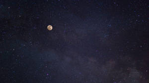 滿月在繁星點點的夜空中閃耀，伴隨著宇宙塵埃雲。 — 月色夜空 壁紙
