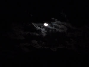 彎月在黑暗夜空中飄動的雲層後發光。