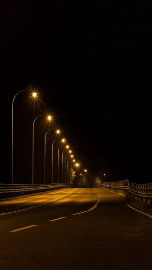 夜晚一條黑暗的道路被一排發光的街燈照亮。