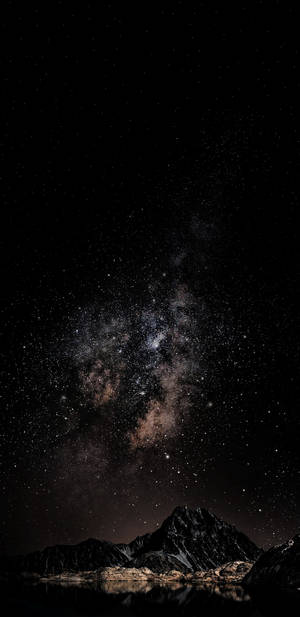 銀河系在黑暗山脈上空，倒映在夜晚的靜止水面上。