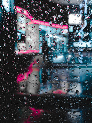 窗戶上的雨滴，伴隨著夜間城市模糊的霓虹燈光。 — 霓虹 iPhone 壁紙