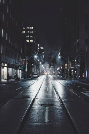 雨夜中濕滑的城市街道，閃爍的路燈和建築物窗戶。