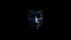 一個帶有無政府主義符號的白色 Guy Fawkes 面具在黑暗中發光。