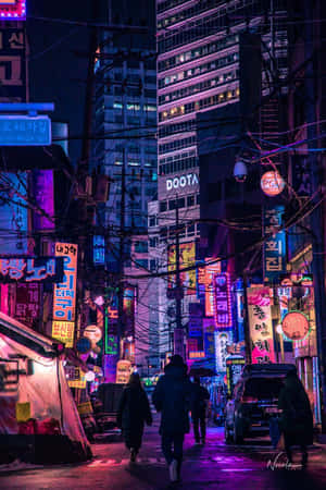 行人夜晚在纏繞的電線下，走過霓虹燈照亮的韓國城市街道。