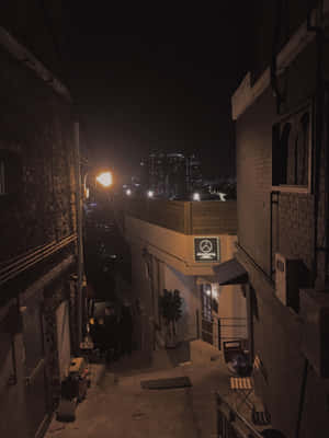 夜晚狹窄的磚砌小巷，溫暖的街燈和遠處的城市天際線。