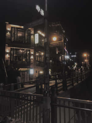 夜晚的城市街道，有發光的招牌和沿著欄杆行走的行人。
