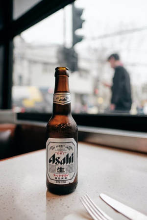 冰凍的朝日啤酒瓶放在檯面上，模糊的城市街道景觀。 — 日本 壁紙