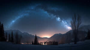 剪影人物在雪地上舉起雙臂，背景是星空、山脈和銀河 — 星星 壁紙
