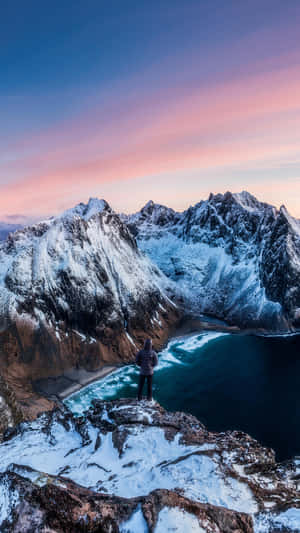 人站在雪崖上俯瞰峽灣和群山（暮色） — 天空景觀 壁紙