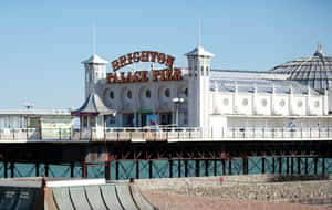 Brighton Palace Pier 延伸至海面，有白色建築和一個大招牌。 — 夏天 壁紙