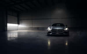在黑暗的工業倉庫中照亮的流線型銀色 Mercedes-AMG GT 跑車。