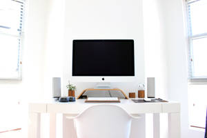 簡約白色家庭辦公室，配備 iMac 和自然光