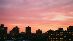 城市建築在粉紅色和橙色日落中映襯出剪影，窗戶閃閃發光。 — 天空 壁紙