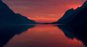 剪影山脈環繞著平靜的湖泊，反射出火熱的夕陽色彩。 — 自然風景 壁紙